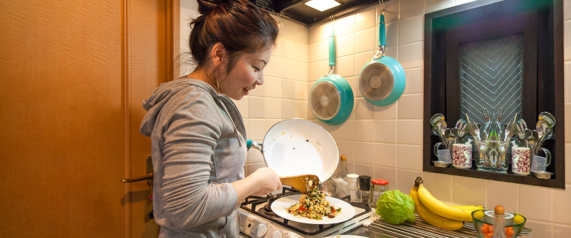 A woman pouring the rice contents out of her frying pan onto a plate looking pleased