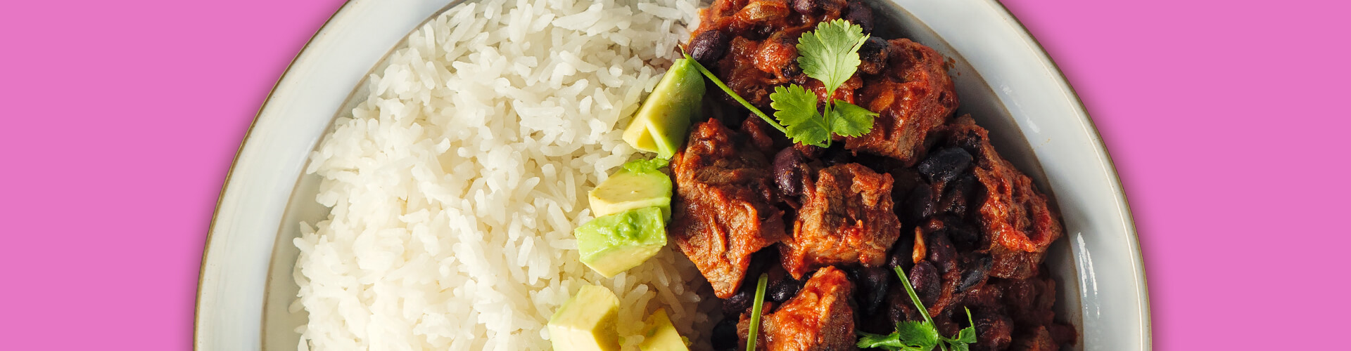 Plate with one side Jasmine Rice and the other side marinated meat divided by avocado slices