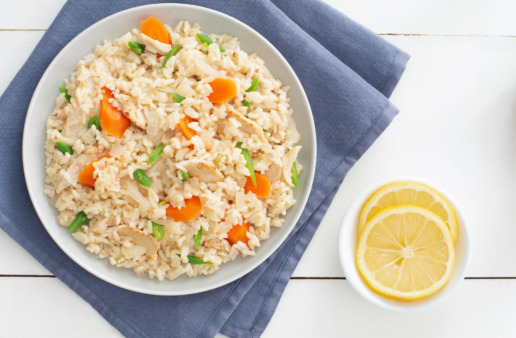 White rice with chopped carrots, green onion, chicken and a side of lemon slices