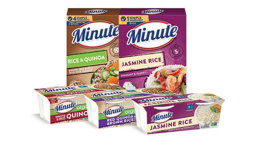 A man standing eating a pastry while a woman stairs into her mug in a kitchen